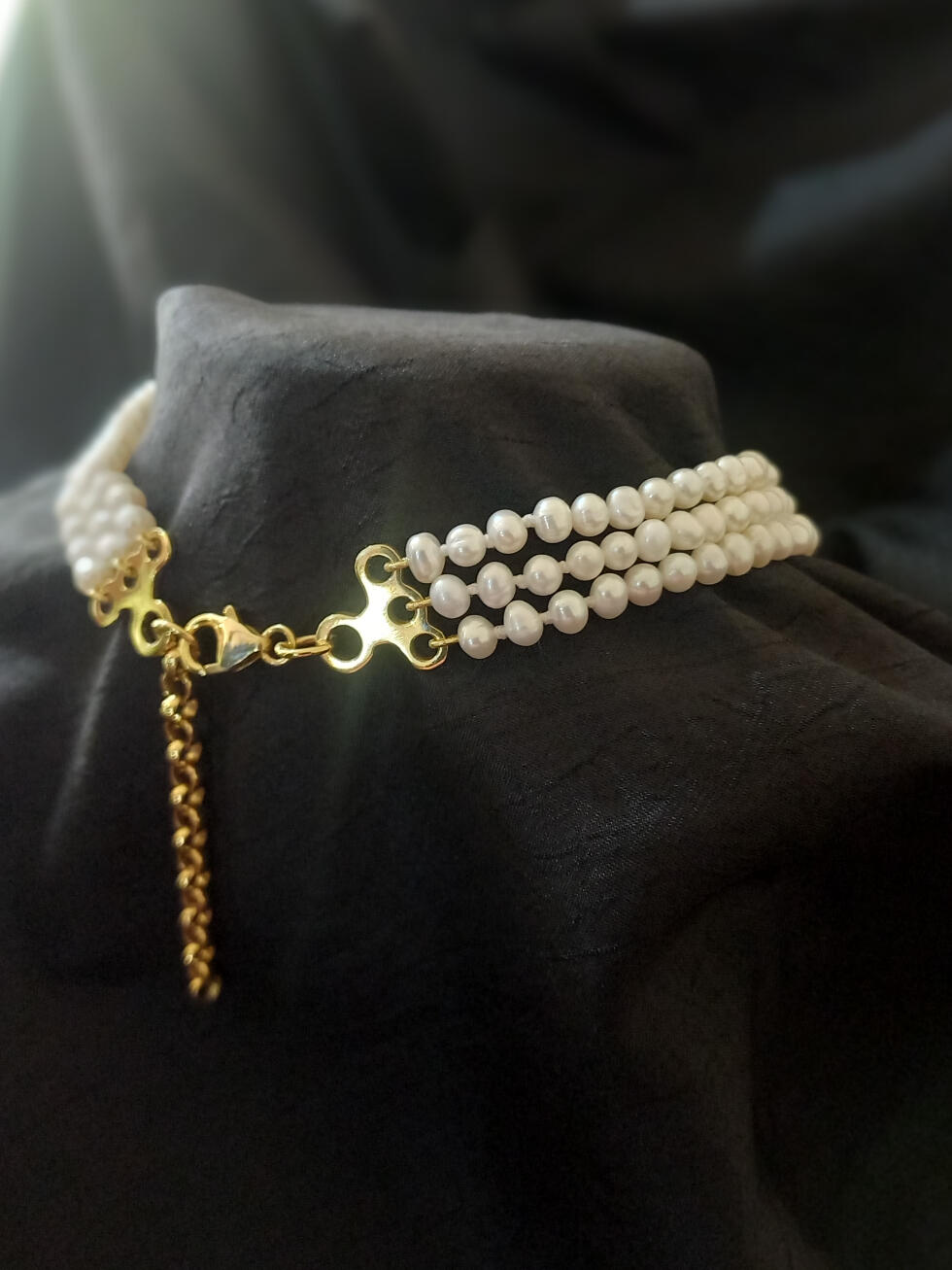 Three-strand unknotted freshwater pearl choker, rear view. Gold-plated findings with gold French wire, lobster clasp, and chain Rear view of a three-strand freshwater pearl choker on gold-plated findings with gold French wire, lobster clasp, and chain to adjust length.